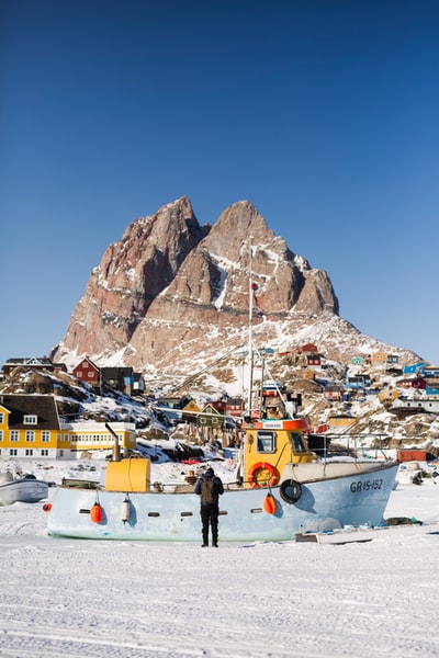 白天，人们站在棕色和白色山脉附近的积雪覆盖的地面上